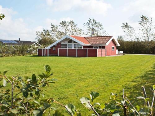 a red house on a large grassy field at 6 person holiday home in Hemmet in Hemmet