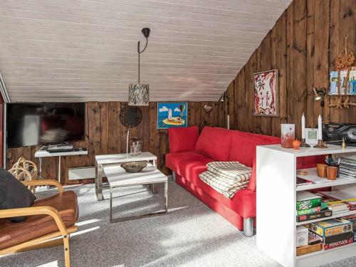 Nørre Nebelにある4 person holiday home in N rre Nebelの赤いソファと木製の壁が備わるリビングルーム