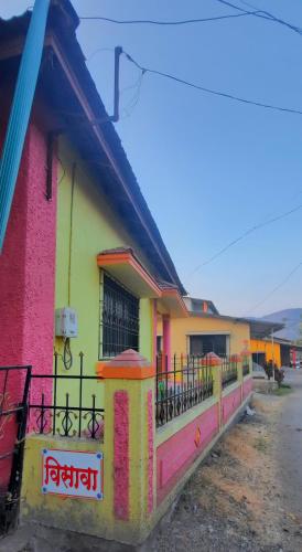 a colorful house with a fence in front of it at VISAVA Home Stay in Alibaug