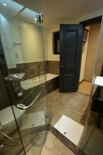 a bathroom with a glass shower and a sink at Fontis Residences Hotel in Kampala