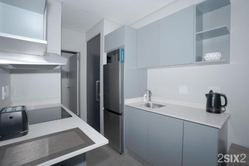 a white kitchen with a refrigerator and a sink at 2SIX2, FLORIDA ROAD in Durban