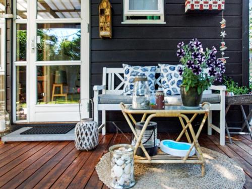 a porch with a bench and a table with flowers at 6 person holiday home in Hemmet in Hemmet