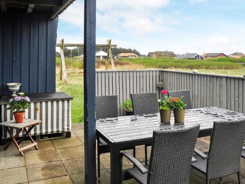 a wooden table and chairs on a patio with flowers at 6 person holiday home in Harbo re in Harboør