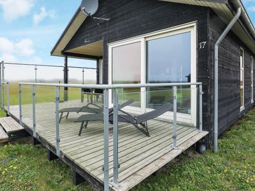 a house with a deck with a chair on it at 4 person holiday home in Harbo re in Harboør