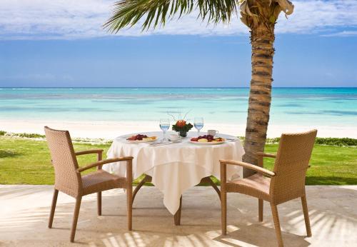 a table and chairs on a beach with the ocean at Tortuga Bay in Punta Cana