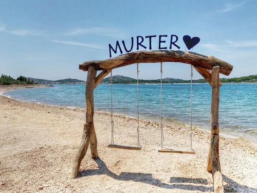 a swing on a beach with a sign that reads winter at Apartments Kostelic in Murter
