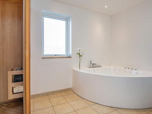 10 person holiday home in Haderslev في هادرسليف: حوض أبيض كبير في الحمام مع نافذة