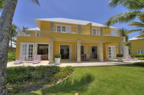 a yellow house with a porch and a yard at Tortuga Bay in Punta Cana