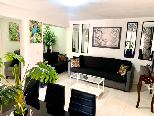 una sala de estar con un sofá negro y algunas plantas en Casita a 3 minutos de la playa con Aire Acondicionado e Internet, en Roquetas de Mar