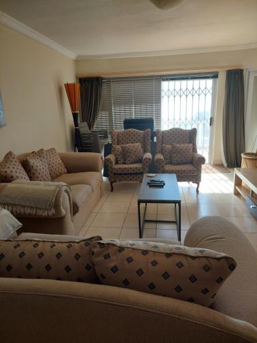 a living room with couches and a table at SYMSTAY Don Diaz in Jeffreys Bay