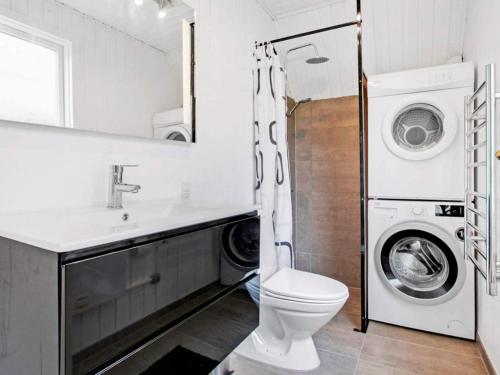 a bathroom with a toilet and a sink and a washing machine at Holiday home Glesborg LXV in Glesborg