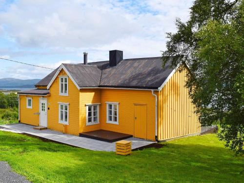 une petite maison jaune assise au-dessus d'une cour dans l'établissement 5 person holiday home in Skutvik, à Skutvika