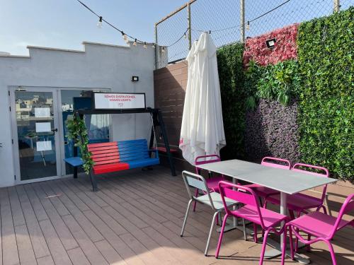 a patio with pink chairs and a table and umbrella at Safestay Madrid Central in Madrid