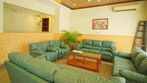 a waiting room with green leather couches and a table at UDS Villa - Next to VFS, Walking to Connaught Place in New Delhi