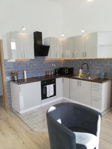 a kitchen with white cabinets and a blue brick wall at Suwałki Centrum Apartments 1 & 2 in Suwałki
