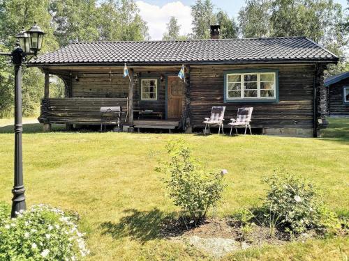 a log cabin with two chairs in a yard at 6 person holiday home in GRANG RDE in Grangärde