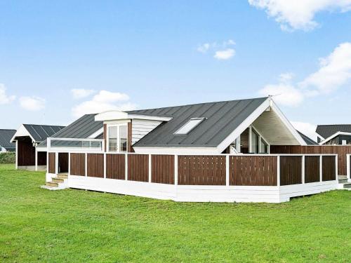 a house with a black roof and a fence at 8 person holiday home in Harbo re in Harboør