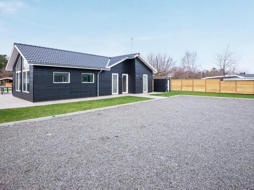 a black house with a gravel driveway at 16 person holiday home in Glesborg in Glesborg