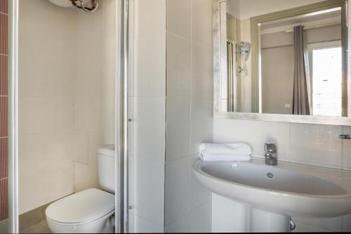 a bathroom with a sink and a toilet and a mirror at Fidias city rooms in Argostoli