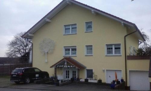 een geel huis met een auto ervoor geparkeerd bij Haus U bis 15 Personen in Usingen