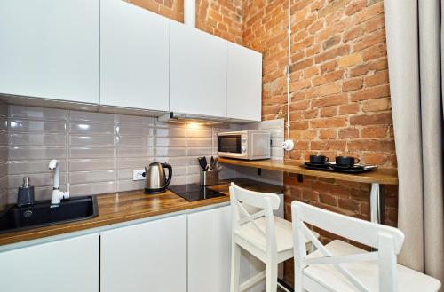 a kitchen with white cabinets and a brick wall at GrandWhite Apart in Saint Petersburg