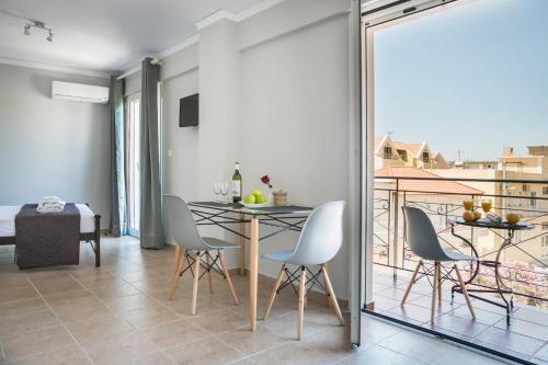 a dining room with a table and chairs and a balcony at Fidias city rooms in Argostoli