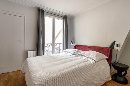 een witte slaapkamer met een bed en een raam bij Bail Mobilite Luxe Le Marais in Parijs