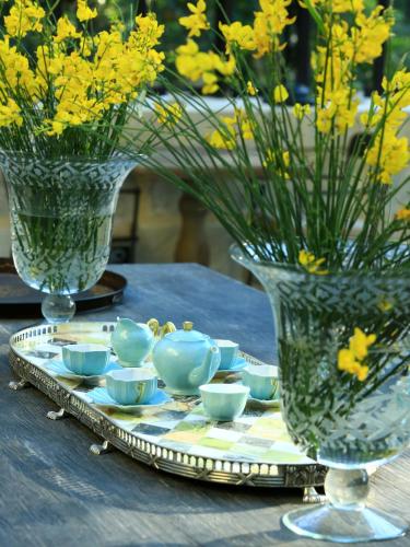 a table with vases and bowls on a tray with yellow flowers at Domaine De Manville in Les Baux-de-Provence