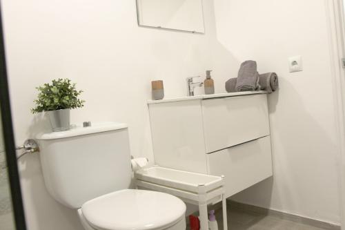 biała łazienka z toaletą i rośliną na półce w obiekcie Estancia en Complejo Tamarán - Playa del Inglés w mieście Playa del Ingles