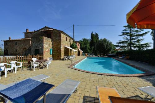 Una piscina con mesas y sillas al lado de un edificio. en Casale le Rondini by VacaVilla, en Lucignano