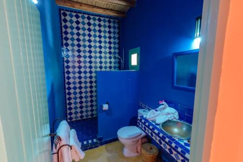 a blue bathroom with a toilet and a sink at Dar El Janoub in Merzouga