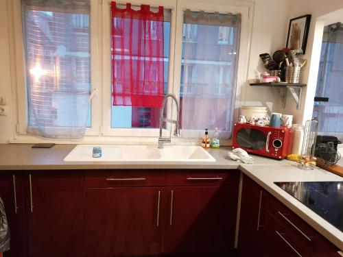 uma cozinha com um lavatório e um micro-ondas vermelho em sur ile du pollet em Dieppe