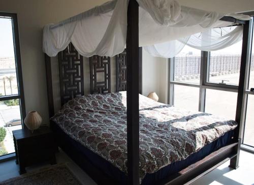 ドバイにあるElegant and comfortably furnished 2BRH apartment in a quiet area!のベッドルーム(天蓋付きベッド1台、窓付)