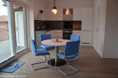 cocina con mesa y sillas azules en una habitación en Fewo Captain Hook Haus Norderney, en Hooksiel