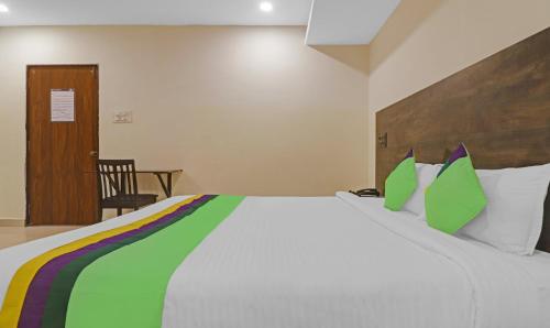 a bedroom with a large white bed with green pillows at Treebo Tee in Hyderabad