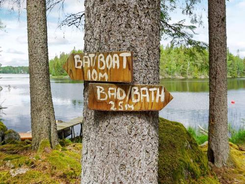 a sign on a tree in front of a lake at 4 person holiday home in Mellösa in Mellösa