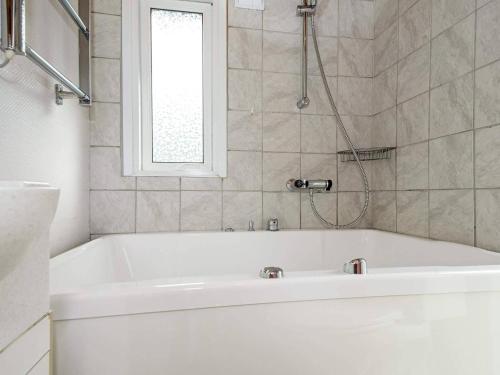 uma banheira branca na casa de banho com uma janela em Holiday home Hovborg II em Hovborg