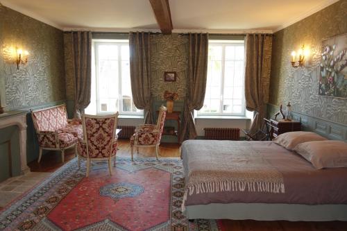 a bedroom with a bed and chairs and windows at Manoir De Savigny in Valognes