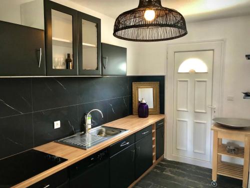 a kitchen with black cabinets and a sink at Les Villas de la Plage in Névez