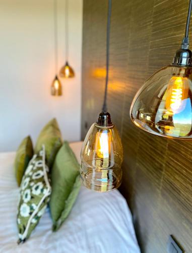 two lights on top of a bed with green pillows at Le Clos du Verger in Aubel