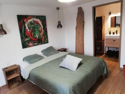 a bedroom with a large bed with a painting on the wall at Le logis du héron in Coulon