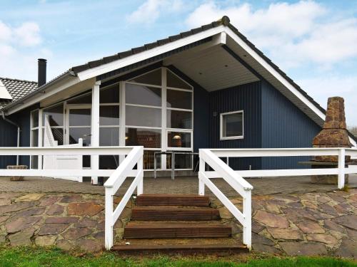 een blauw huis met een witte veranda en een trap bij 8 person holiday home in Vinderup in Vinderup