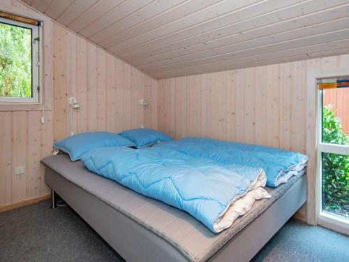 Bett mit blauen Kissen in einem Zimmer mit Fenster in der Unterkunft Holiday home Ebeltoft CXLVIII in Ebeltoft