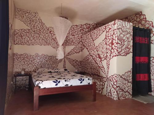 a room with a bed and a wall with curtains at Chez Yaya - Grande Chambre in Oussouye