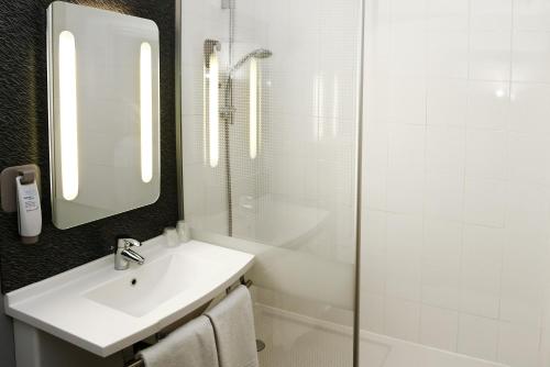 a white bathroom with a sink and a shower at ibis Orange Centre in Orange