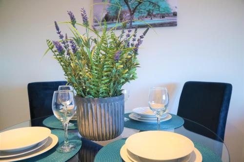 a table with plates and glasses and a vase with flowers at The Ilkley Penthouse in Ilkley