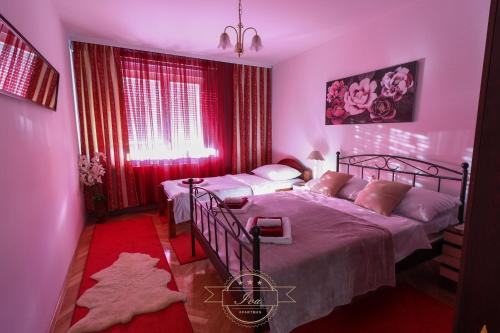 a bedroom with two beds and red curtains at Apartman IVA, Donji Miholjac in Donji Miholjac