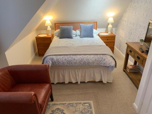 a bedroom with a bed with blue pillows and a chair at 83 in Aylesbury