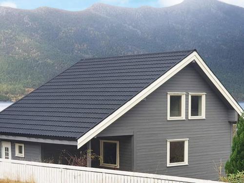 une maison avec un toit noir et des montagnes en arrière-plan dans l'établissement 8 person holiday home in Svelgen, à Svelgen