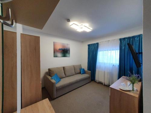 a living room with a couch and blue curtains at Pensiunea Black Mountain in Baia-Sprie